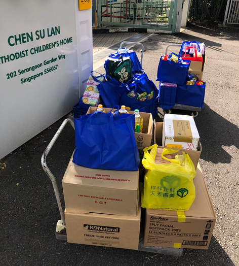 Donation boxes and blue reusable bags stacked on trolleys outside Chen Su Lan Methodist Children's Home in Singapore.